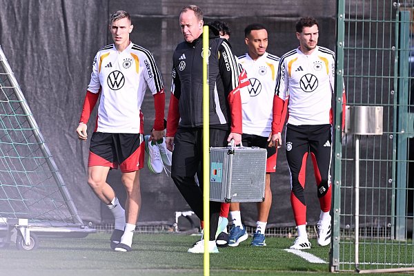 Mit Teamarzt Hahne (2.v.l.) betritt Schlotterbeck (l.) den Trainingsplatz. - © David Inderlied/dpa