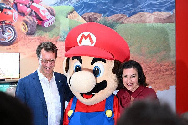Beim Messerundgang über die Gamescom kam der Tross von Politikern auch beim Messestand von Nintendo vorbei, hier stehen NRW-Ministerpräsident Hendrik Wüst (CDU) und Bundesforschungsministerin Dorothee Bär (CSU) neben einer Mario-Plüschfigur. - © Wolf von Dewitz/dpa