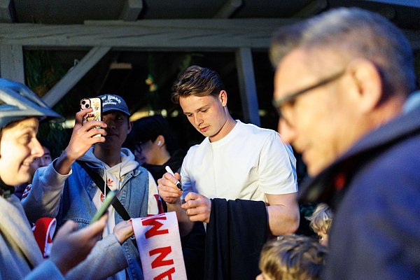 Torhüter Jonas Urbig schreibt Autogramme, bevor er mit seinen Teamkollegen feiert. - © Matthias Balk/dpa