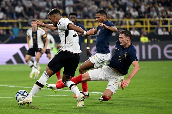 Benjamin Henrichs (l) wird von Frankreichs Benjamin Pavard attackiert. - © Federico Gambarini/dpa