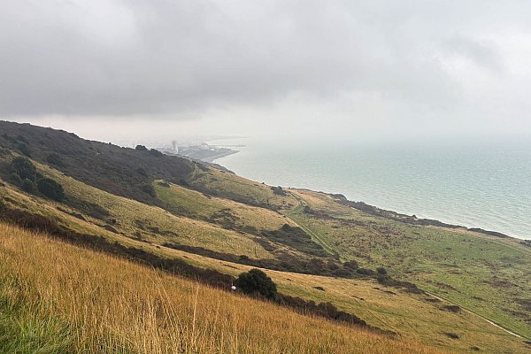 Nach fünf Stunden Fußweg tut sich hinter einem grünen Hügel das Ziel auf: Eastbourne liegt verwaschen da. - © Nathalie Helene Rippich/dpa-tmn