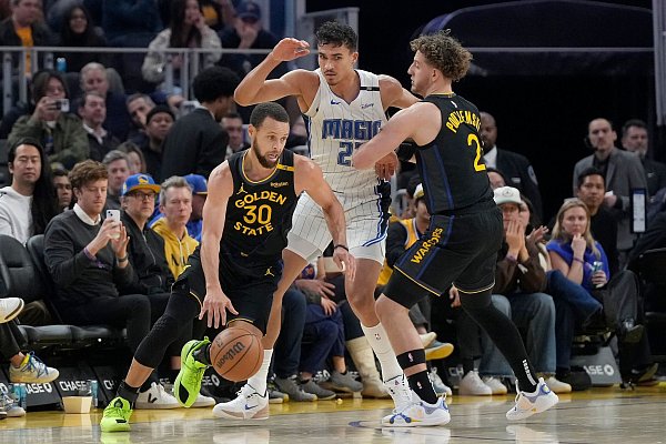 Orlandos Tristan da Silva (Mitte) sammelte gegen All-Star Stephen Curry (l.) zwei Pünktchen. - © Jeff Chiu/AP/dpa