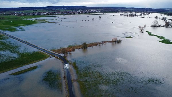 Ein Auto fährt am Rande des aufgestauten Rückhaltebeckens der Ohm. In Hessen ist noch keine Entspannung beim Hochwasser in Sicht. - © Nadine Weigel/dpa