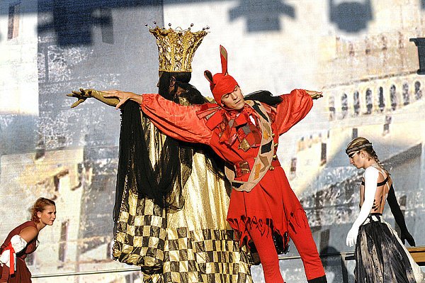 Szene aus der "Carmina Burana"-Aufführung im Ravensberger Park. Im Schein der Abendsonne werfen drei Beleuchtungskörper Schatten auf den oberen Rand des Bühnenhintergrunds. - © FOTO: BARBARA FRANKE