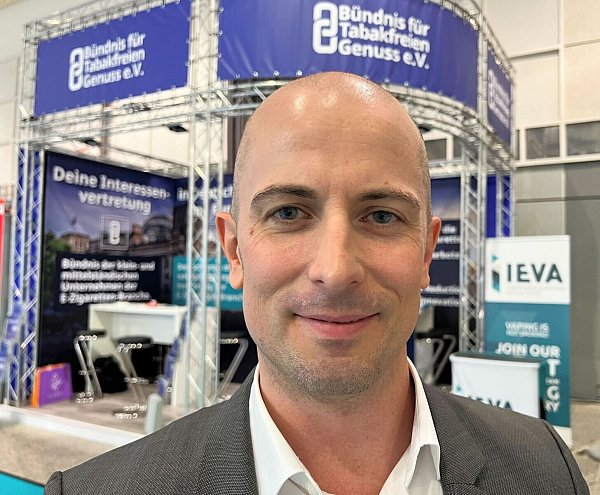 Dustin Dahlmann, Vorsitzender des E-Zigaretten-Verbandes «Bündnis für Tabakfreien Genuss» (BfTG), steht bei der Messe Intertabac 2023 vor einem Stand seiner Organisation. - © Wolf von Dewitz/dpa