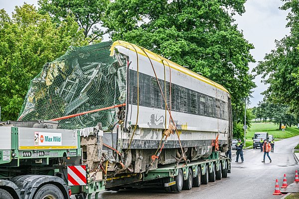Ein verladener Zug Wagon steht an der Unfallstelle, an der ein Regionalzug entgleist ist. Ein Regionalexpress war am Sonntagabend (27.07.2025) in Riedlingen nach bisherigen Erkenntnissen infolge eines Hangrutsches entgleist. - © Jason Tschepljakow/dpa