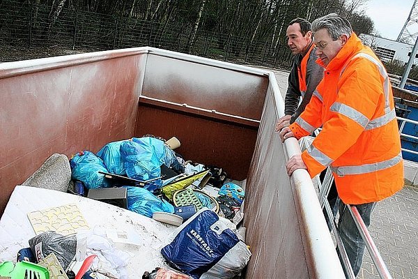 Michael Kuntze (GEG) und Reinhard Gebauer (Stadtreinigung/ v. l.) prüfen, dass in diesem Container nur Restmüll landet. - © FOTO: HOLGER KOSBAB