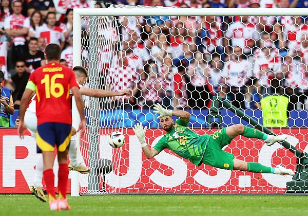 Spaniens Torhüter Unai Simon (r) hält einen Elfmeter von Kroatiens Bruno Petkovic (hinten l). - © Andreas Gora/dpa