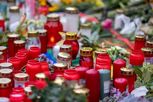 Kerzen und Blumen erinnern an die Opfer der Messerattacke. - © Thomas Banneyer/dpa