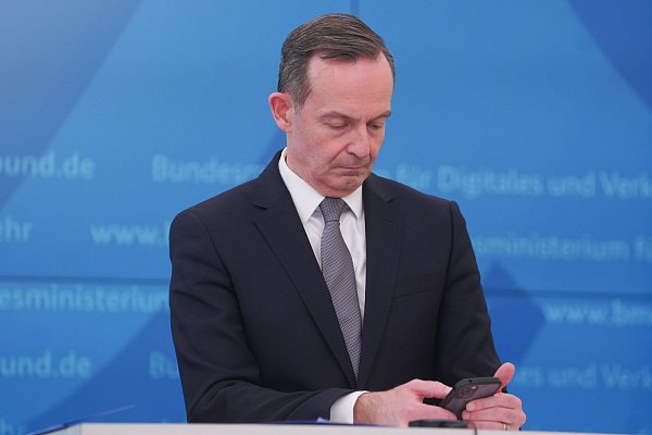 Bundesverkehrsminister Volker Wissing (FDP) blickt bei einer Pressekonferenz im März 2022 auf sein Smartphone. - © Joerg Carstensen/dpa