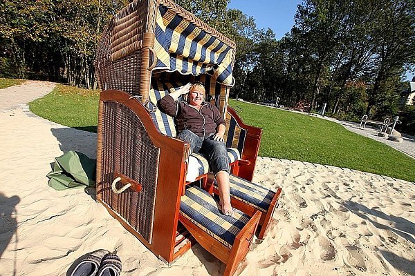 Ilona Simon-Splinter hat ihre Schuhe im Sand zurückgelassen und den Strandkorb zur Sonne ausgerichtet. Die 50-Jährige ist Übernachtungsgast in der Ems-Erlebniswelt und genießt den Garten mit dem symbolisierten Verlauf der Ems. - © FOTO: KUBENDORFF