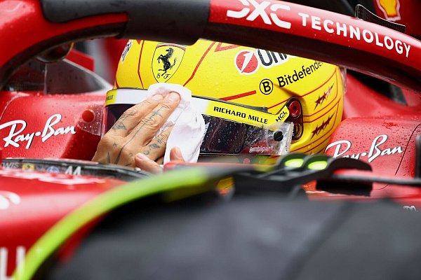 Lewis Hamilton wischt sich den Regen vom Visier. - © Yves Herman/Pool Reuters/AP/dpa