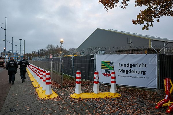 Polizisten laufen vor dem temporären Gerichtsgebäude des Landgerichtes Magdeburg Streife. - © Jan Woitas/dpa