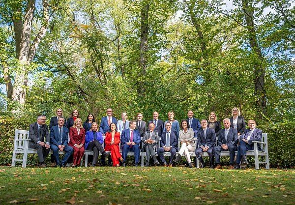 Beim Gruppenfoto trägt der Kanzler wieder den gewohnten Look. - © Michael Kappeler/dpa