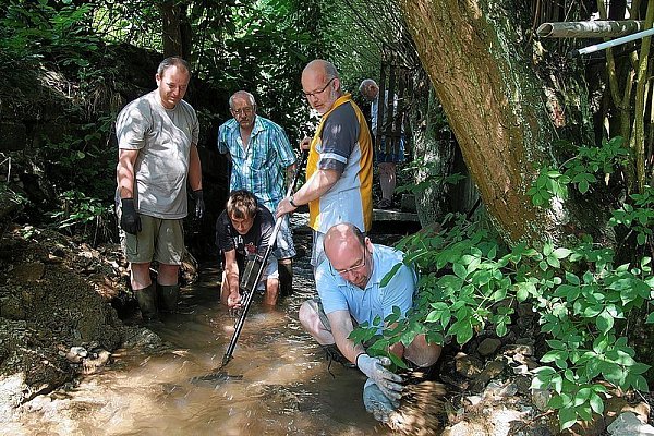 Volker Spitz (v. l.), Hendrik und Vater Burkhard Wiemers, Friedhelm Giefers und Frank Schneider suchen mit einem Minensuchgerät den Hellbach ab. Mit Gummistiefeln und Handschuhen waren die Männer am Werk und drehten jeden Stein um. - © FOTO: KURT DIESTERHEFT