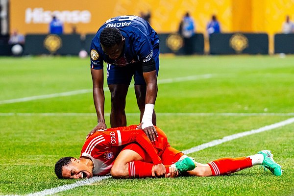 Jamal Musiala liegt mit starken Schmerzen verletzt am Boden. PSG-Profi William Pacho kümmert sich um ihn. - © Malachi Gabriel/ZUMA Press Wire/dpa