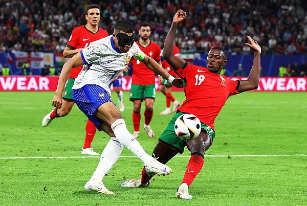 Frankreichs Kylian Mbappé (l) und Portugals Nuno Mendes kämpfen um den Ball. - © Jens Büttner/dpa