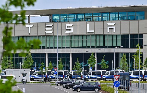 Polizeifahrzeuge stehen am Samstagvormittag vor dem Haupteingang des Tesla-Werks in Grünheide. - © Patrick Pleul/dpa