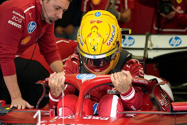 Mit gelbem Helm im roten Auto. - © Darko Bandic/AP/dpa