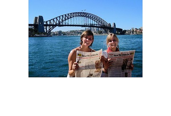 Simone Trysna (l.) und Laura Delkeskamp haben im Weihnachtspaket der Eltern die Neue Westfälische gefunden – und informieren sich vor der Harbour Bridge in Sydney über die Kurstadt. - © FOTO: PRIVAT