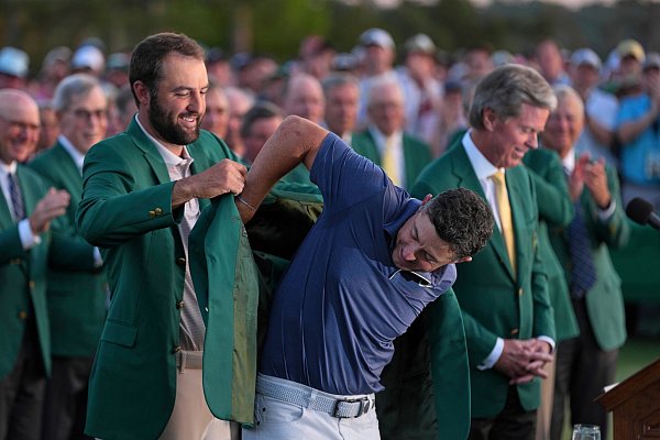 Vorjahressieger Scottie Scheffler streifte McIlroy das grüne Jackett über. - © Matt Slocum/AP/dpa