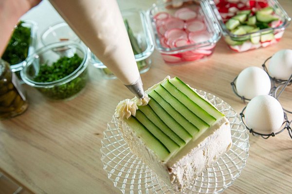 Auf der Gurkenschicht wird mit einem Spritzbeutel Frischkäse in Rosettenform aufgespritzt. - © Christin Klose/dpa-tmn
