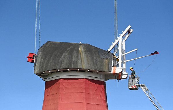 Mit einem Autokran wurde die tonnenschwere Kappe wieder auf die Mühle gesetzt. - © Lars Penning/dpa