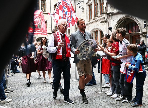Bundesliga-Torschützenkönig Harry Kane trägt die Meisterschale flankiert von Oberbürgermeister Dieter Reiter (mit Fanschal) ins Münchner Rathaus. - © Daniel Löb/dpa