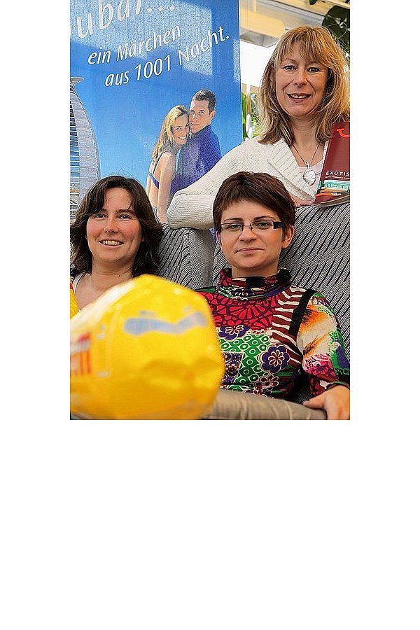 Neben Anja Düker (v. l.) und Anna Reineke ist noch Platz in der Fliegersitzreihe in Schröders Reisetreff, Bad Driburg. Sie beraten als Reiseverkehrsfachfrauen, gemeinsam mit Anke Sommer (stehend), gerne über nahe und ferne Ziele. - © FOTO: SABINE BRINKMANN
