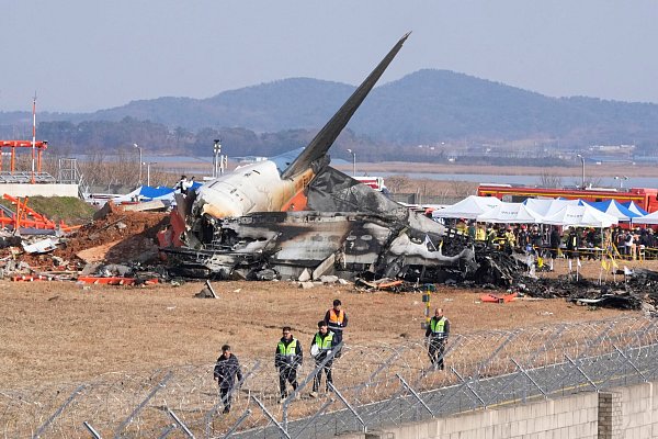 Feuerwehrleute und Rettungskräfte bergen die Opfer des verunglückten Flugzeugs auf dem internationalen Flughafen von Muan. - © Ahn Young-joon/AP/dpa