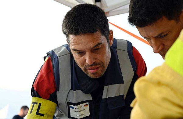 Simon Friz (links), Teamleiter der insgesamt 67 Feuerwehrleute aus Bonn, Düsseldorf und Celle, die bei der Bekämpfung schwerer Waldbrände in Spanien geholfen haben, bei einer Einsatzbesprechung. Für die Deutschen ging es auch darum, das Wissen ihrer südeuropäischen Kollegen mit nach Deutschland zu nehmen. (Archivbild) - © Sven Käuler/dpa