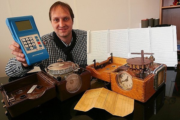 Markus Motz präsentiert verschiedene Generationen von Taubensportuhren. Die manuelle Technik und handgeschriebene Listen haben inzwischen ausgedient. Heute wird die Geschwindigkeit der Tauben mit der grauen Antennenplatte und dem blauen Messgerät gestoppt, die in Höxter entwickelt wurden. - © FOTO DAVID SCHELLENBERG
