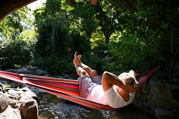 Ein Mann schaukelt im Berliner in einer Hängematte über dem Wasser. - © Katharina Kausche/dpa