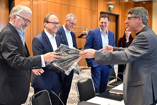 Zum Beginn der Tarifverhandlungen in der Stahlindustrie überreicht der Verhandlungsführer der IG Metall, Knut Giesler, zwei T-Shirts an den Verhandlungsführer der Arbeitgeber, Reiner Blaschek (2.v.l), sowie den Geschäftsführer des Arbeitgeberverbandes Stahl, Gerhard Erdmann (l). - © Federico Gambarini/dpa