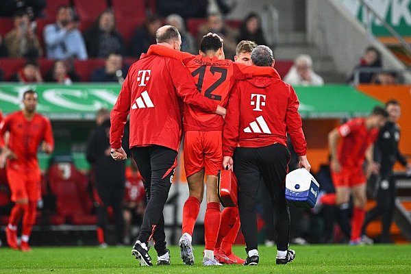 Der verletzte Jamal Musiala (M) muss beim Verlassen des Platzes gestützt werden. - © Tom Weller/dpa