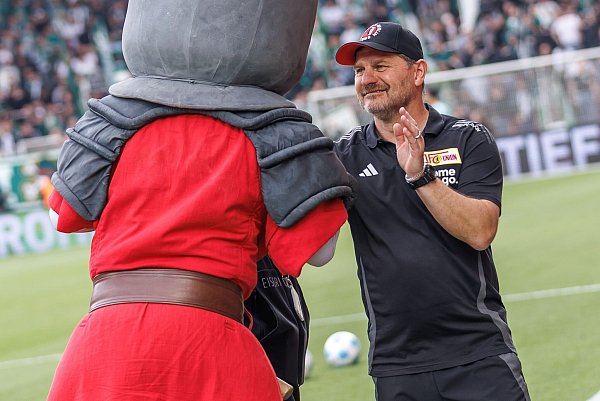 Union-Trainer Steffen Baumgart hat Zeit für einen Handshake mit dem Club-Maskottchen. - © Andreas Gora/dpa