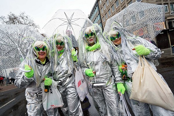 Jecken schützen sich beim traditionellem Kö-Treiben auf der Düsseldorfer Königsallee mit Schirmen vor dem Regen. - © Henning Kaiser/dpa