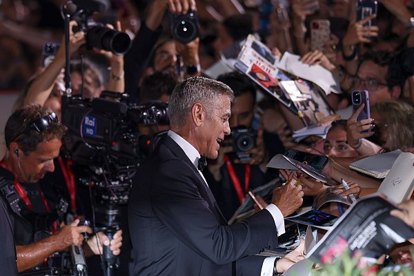 George Clooney gab schon vergangenes Jahr Autogramme in Venedig - nun kommt er zurück (Archivbild). - © Vianney Le Caer/Invision/AP/dpa