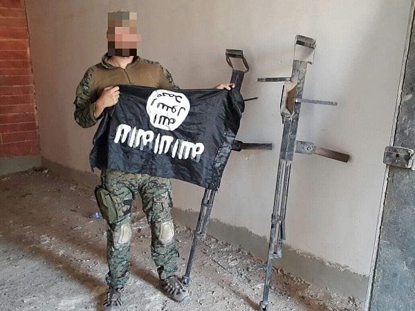 In Syrien: Der 22-Jährige zeigt eine Flagge des IS, der bekämpft wird, hoch. - © Privat