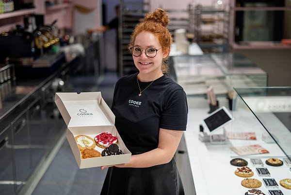 Eine Box mit frisch gebackenen und belegten Cookies präsentiert Mitgründerin Julia Boes. - © Christoph Schmidt/dpa
