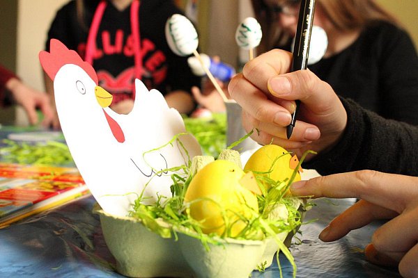 Konzentration gefragt: Emily (10) schneidet aus Tonkarton ein Huhn aus, das sie mit einem orangefarbenen Schnabel und einem roten Kamm verschönert. Anschließend bemalt sie hartgekochte Eier mit gelber Wasserfarbe, damit ihr Huhn Küken bekommt. - © Corinna Schwanhold