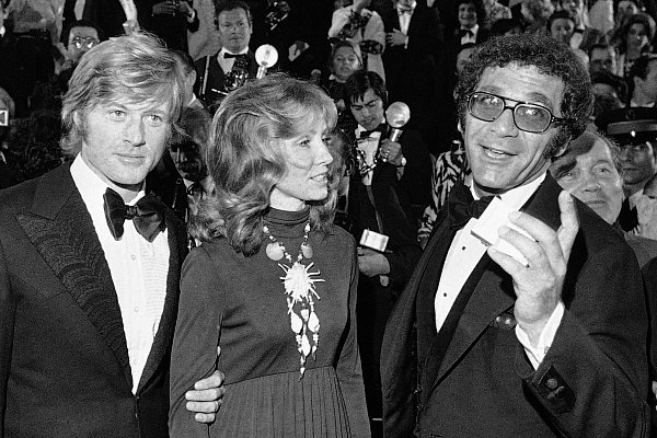Robert Redford (v. l.), seine damalige Frau Lola und Regisseur Sydney Pollack erscheinen 1972 bei der Präsentation des Films „Jeremiah Johnson“ während der Filmfestspiele in Cannes. - © Jean-Jacques Levy/AP/dpa