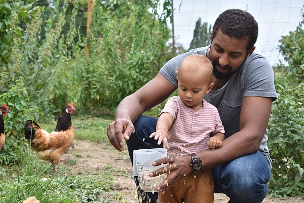 Manchmal muss Papa helfen: Amadou und der kleine Amar bringen Futter unter das Hühnervolk. - © Svenja Ludwig