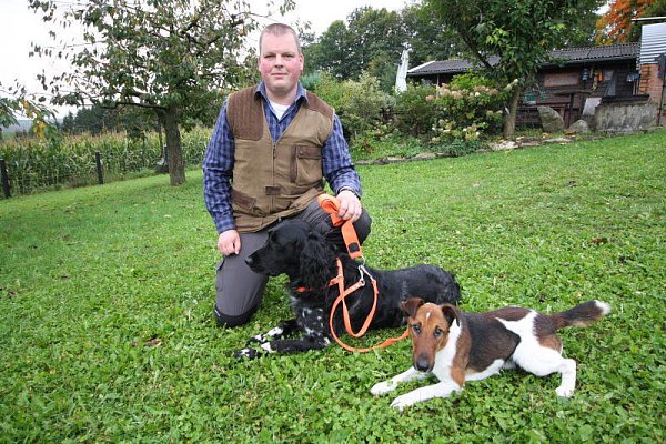 Unterschiedliche Charaktere: Matthias Schneider (34) mit Xandor (5), dem Großen Münsterländer, und dem Foxterrier Xeros (2) an der Hütte im Grünen. - © NW