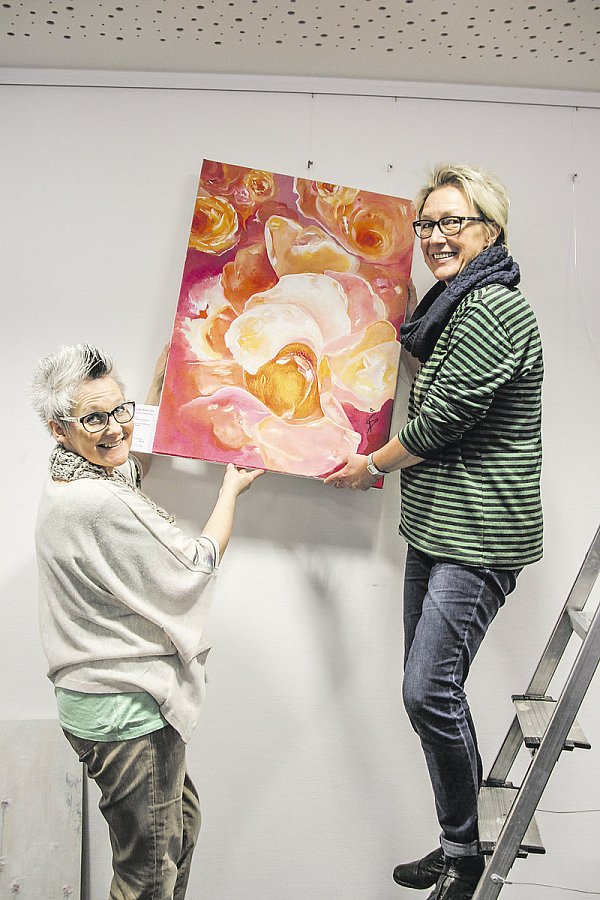Aufbau: Die Steinheimer Künstlerinnen Sabine Diedrich (l.) und Annette Kaiser haben für jedes ihrer Werke einen passenden Platz auf der großen Ausstellungsfläche gefunden. Gezeigt werden insgesamt rund 55 Bilder zum Thema "Blütezeit". - © Foto: Madita Schellenberg