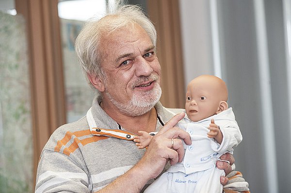 Rüdiger Prinz mit einer Puppe, die körperliche Symptome einer Alkoholschädigung wie tief angesetzte Ohren zeigt. - © FOTO: JÖRG DIECKMANN