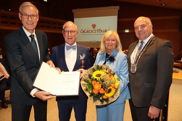 Das Bundesverdienstkreuz am Bande steckt schon am Revers: Landrat Sven-Georg Adenauer (l.) und Bürgermeister Hubert Erichlandwehr gratulieren Ralf und Uschi Heibrok. Als Vereinslogo hat die „Glückstour“ ein pochendes Herz. - © Sigurd Gringel