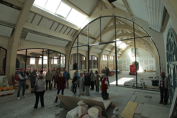 Gut beleuchtet: Über den 30 Interessierten eines Rundgangs durch die neugestaltete Markthalle mit Markthallenmanagerin Silke Mittmann sind die neuen Dachfenster zu erkennen, die mit ein Grund für die Kostensteigerungen sind. - © Peter Steinert