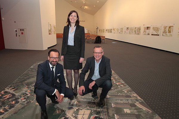 Entwicklungsfläche: Norbert Landshut (Geschäftsführer der Stadtentwicklungsgesellschaft), Stadtplanerin Sarah Liebing und Marta-Direkto Roland Nachtigäller auf einem Bild des Bildungscampus im Ausstellungsraum des Marta-Museums. - © Peter Steinert