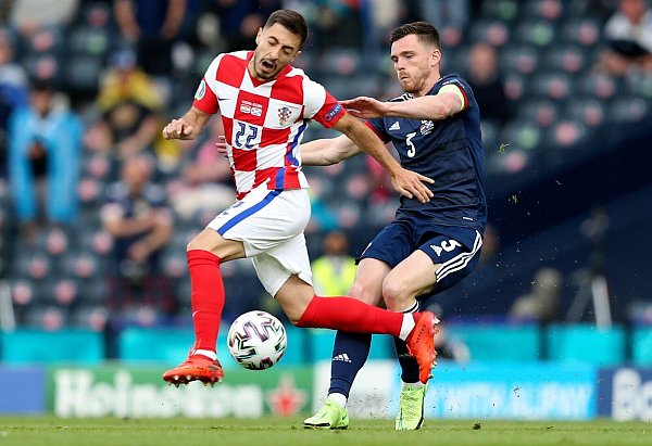 Kroatiens Josip Juranovic (l) und Schottlands Andrew Robertson kämpfen um den Ball. - © Robert Perry/EPA Pool/AP/dpa